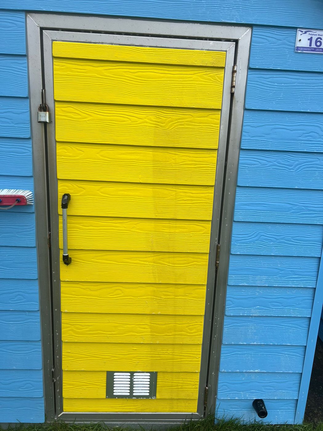 A bright yellow-doored beach hut cleaned and freshened on the West Sussex coast