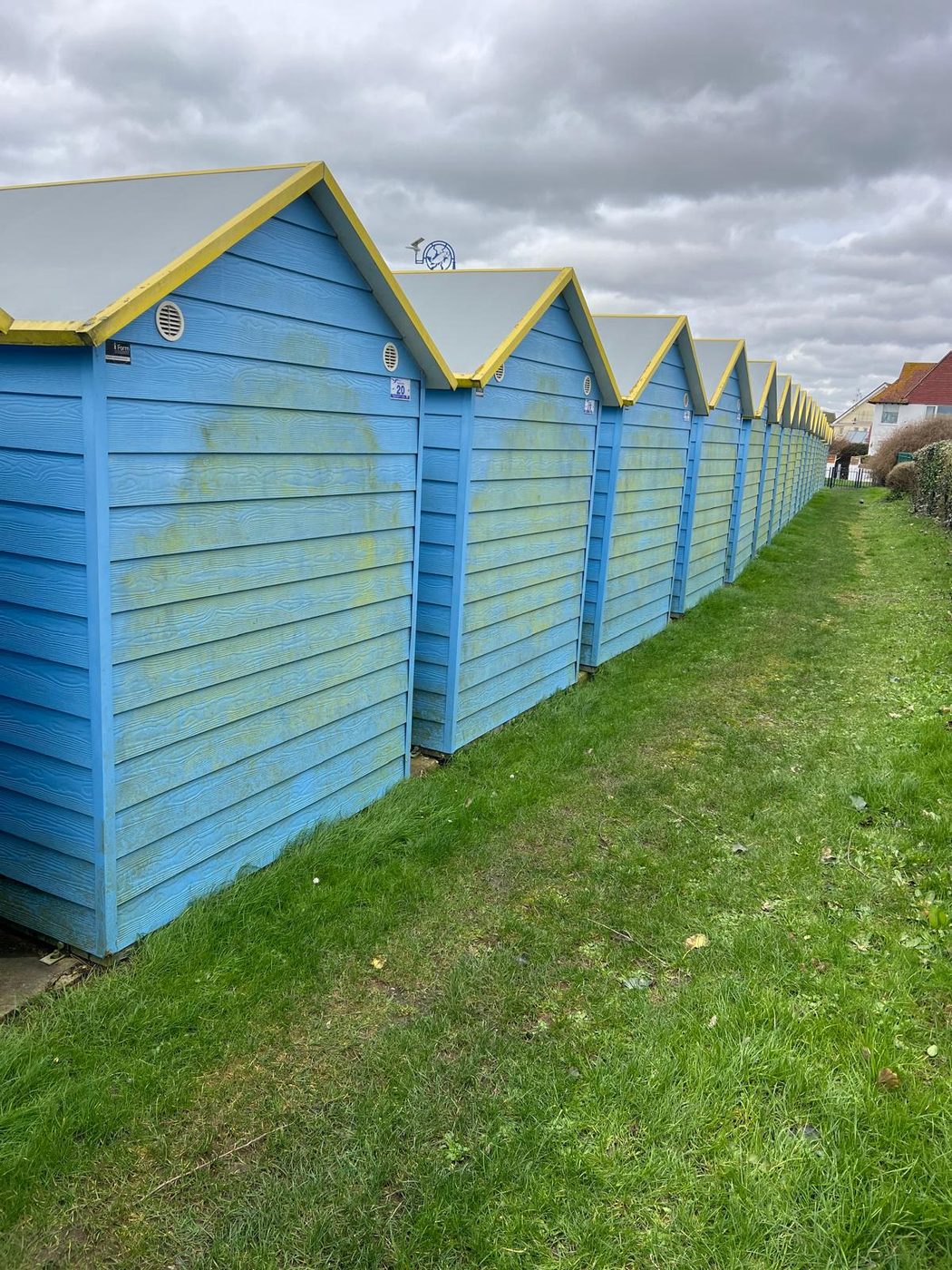 A long row of blue beach huts soft washed along the coast in West Sussex