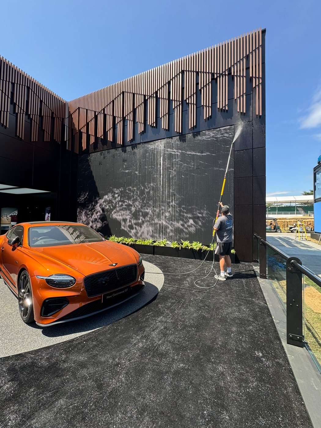 Operative soft washing the dark cladding of the Bentley Pavilion at the Goodwood Festival of Speed