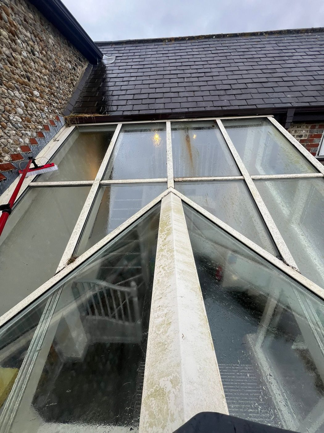 A glass conservatory roof cleaned clear of moss and algae in West Sussex