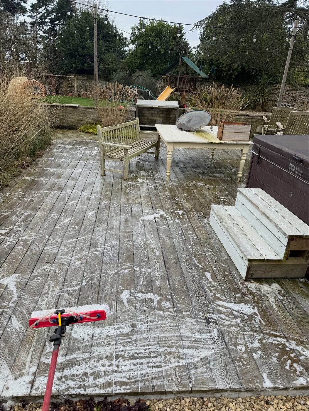 Timber decking being soft washed and rinsed clean