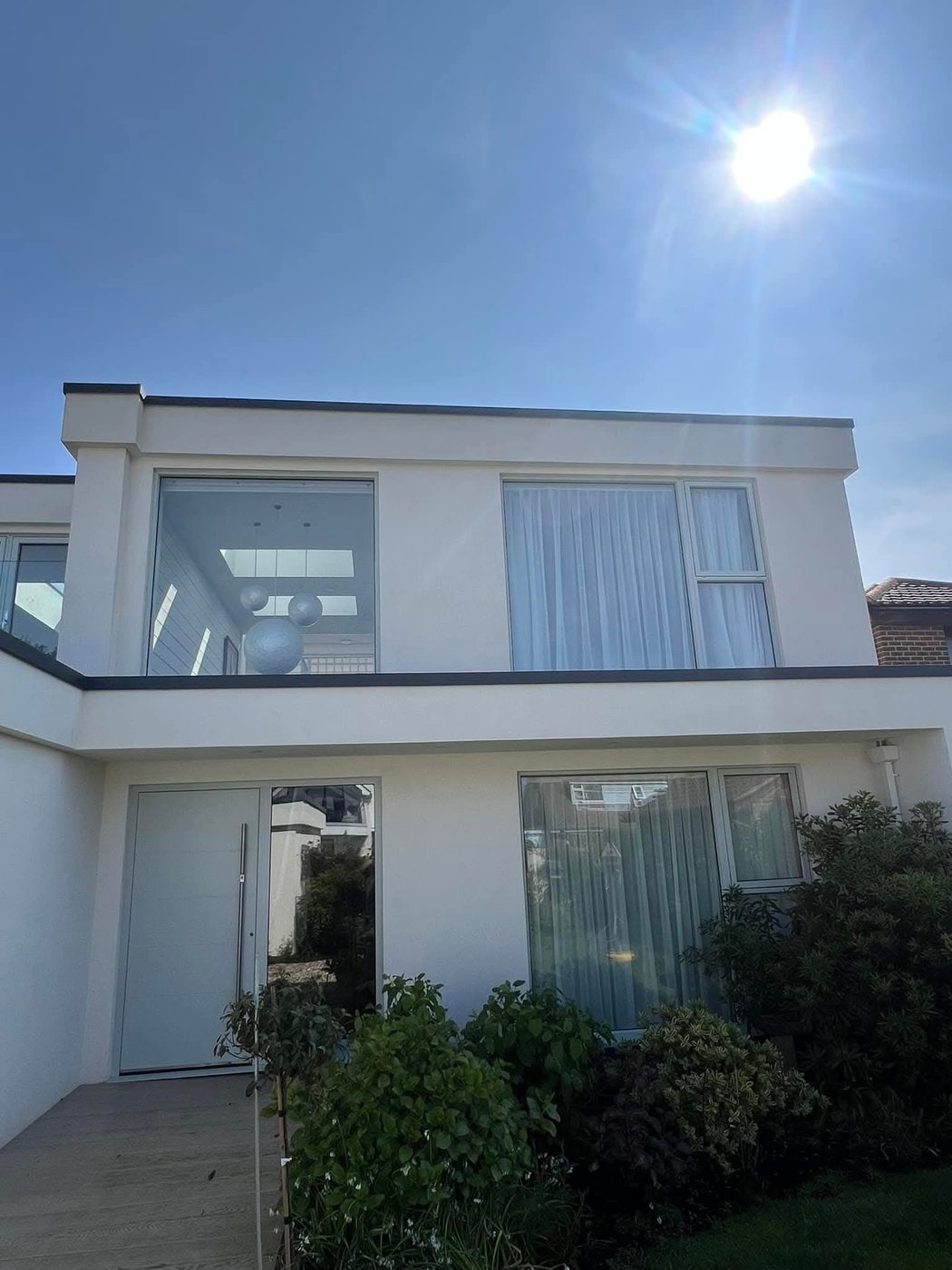A white rendered modern coastal home in the sun