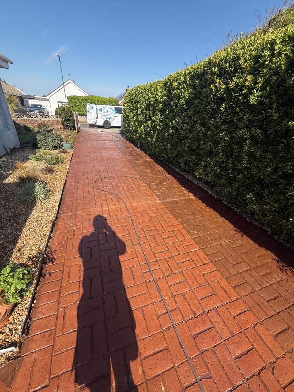 A red block-paved path cleaned alongside a hedge in West Sussex